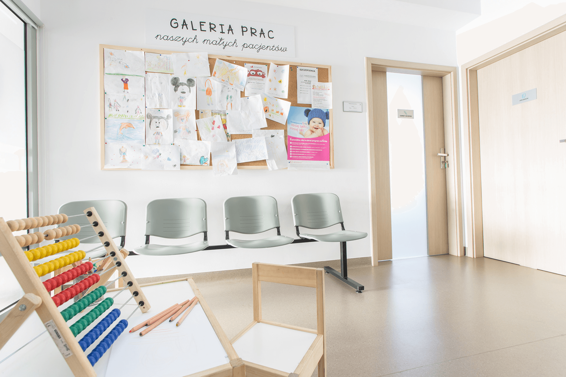 Poczekalnia pediatryczna z galerią prac dzieci, stolikiem do zabawy i kolorowym liczydłem
