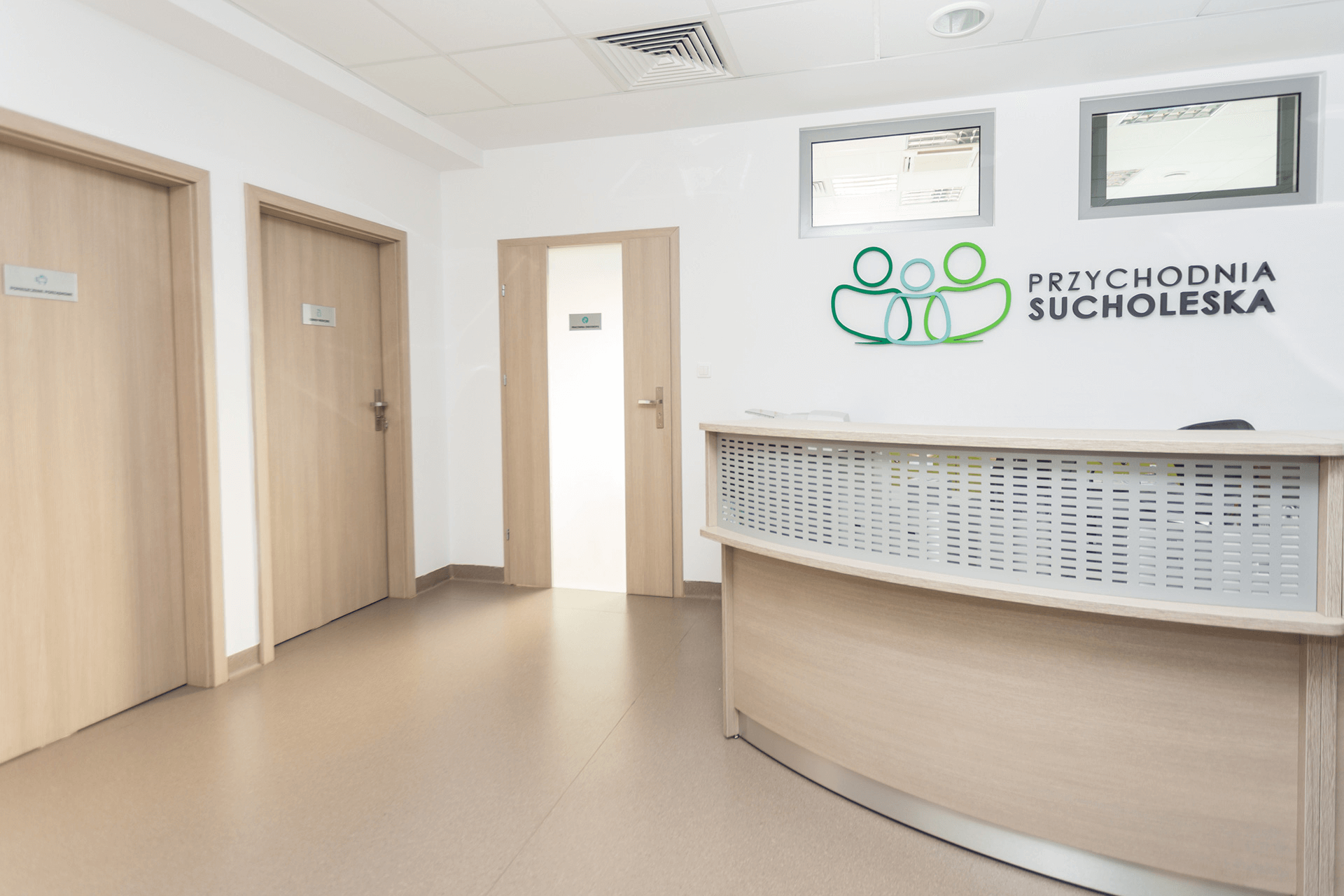 Recepcja Przychodni Sucholeskiej z logo na ścianie i jasnym, nowoczesnym wnętrzem